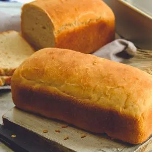 Freshly baked loaves of bread made with War Eagle Mill Organic Whole White Wheat Flour, shown golden brown and sliced on a rustic cutting board.