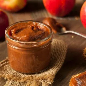 War Eagle Mill Apple Butter – Open Jar Open jar of War Eagle Mill Apple Butter on burlap with apples in background – rich, smooth texture and warm, spiced flavor.
