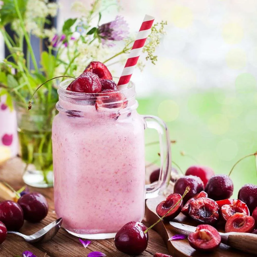 Glass of flax meal smoothie with strawberries, cherries, and banana on rustic table.