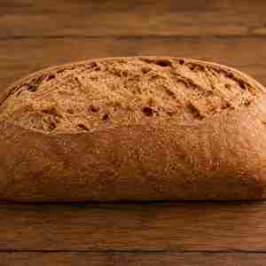 Rustic Rye Sourdough Loaf - War Eagle Mill Food Group Rustic round loaf of crusty brown bread on a wooden table surface.